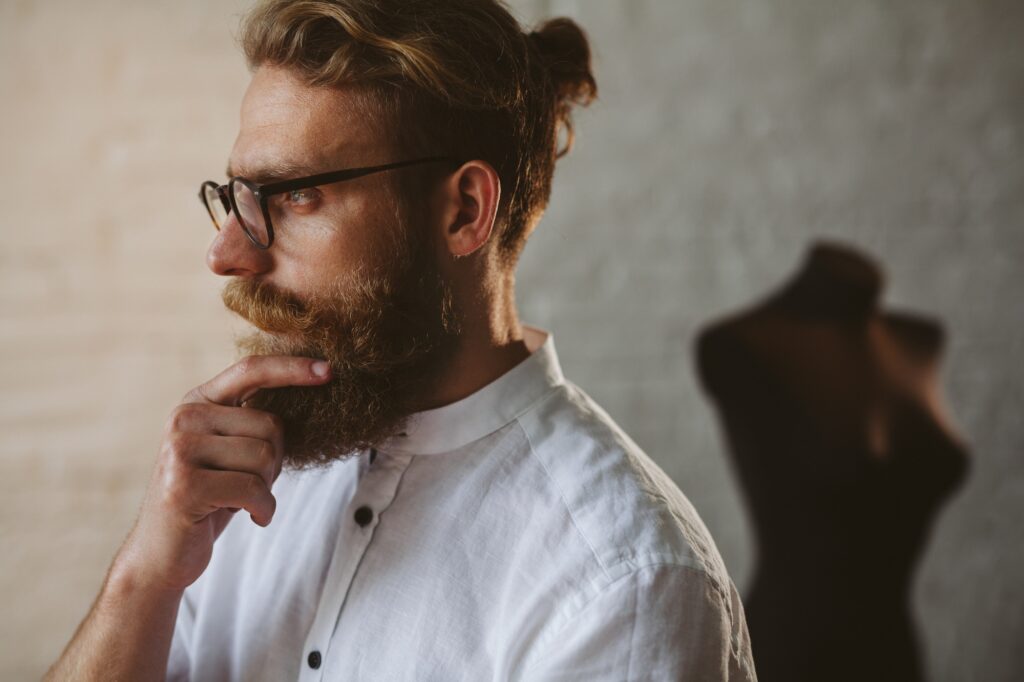 Bearded man wearing glasses touching chin